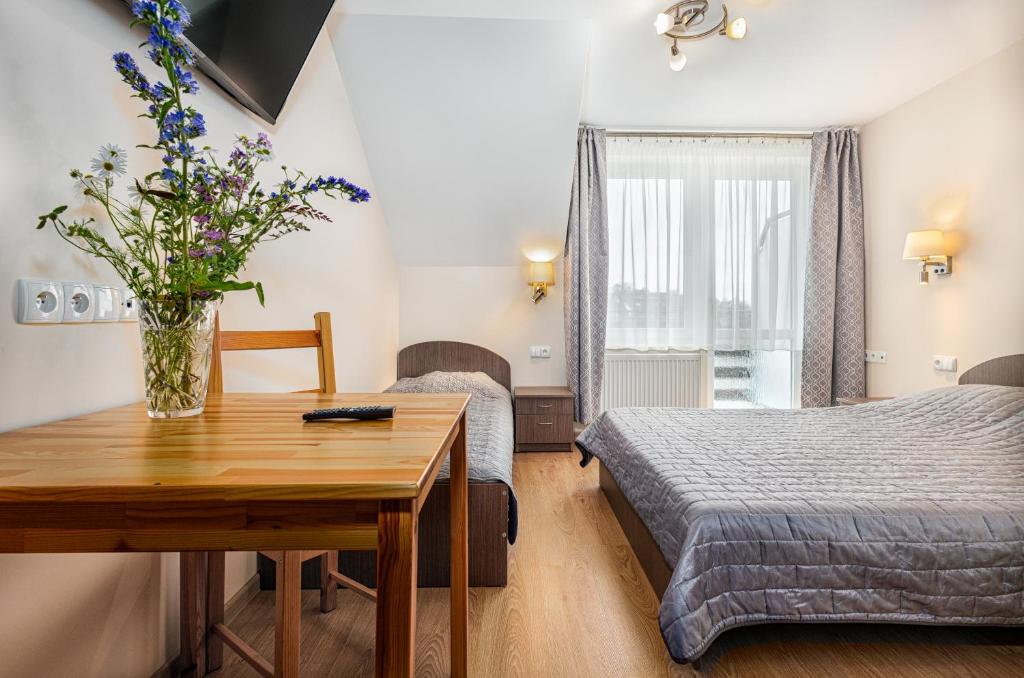 a bedroom with two beds and a table with a vase of flowers at Willa Wilk Morski in Jastrzębia Góra