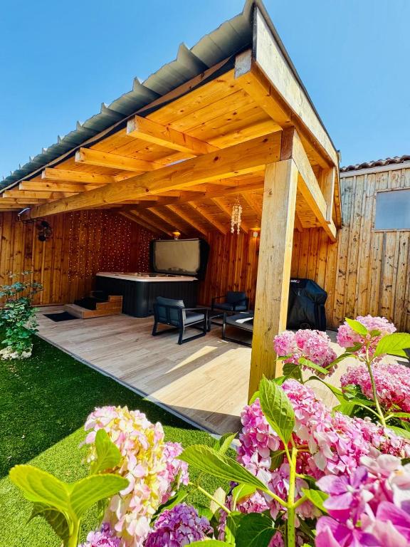 une pergola en bois avec une télévision dans un jardin dans l'établissement La Bulle Médocaine - JACUZZI- Tout confort, à Macau