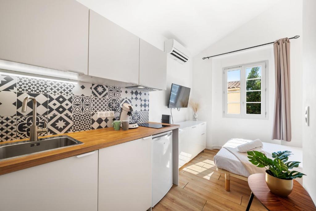 une cuisine avec des armoires blanches, un évier et une fenêtre dans l'établissement Studio Cosy Vieille Ville, à Saint-Laurent-du-Var