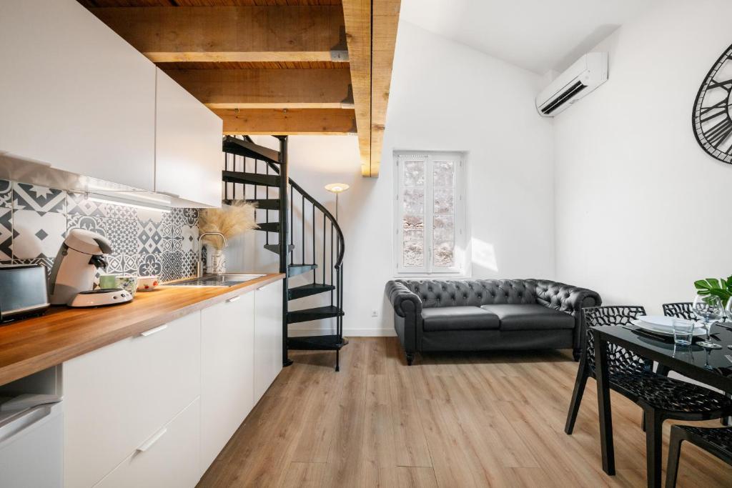 Il comprend une cuisine et un salon avec un escalier et un canapé. dans l'établissement Évasion en duplex au cœur de la vieille ville, à Saint-Laurent-du-Var