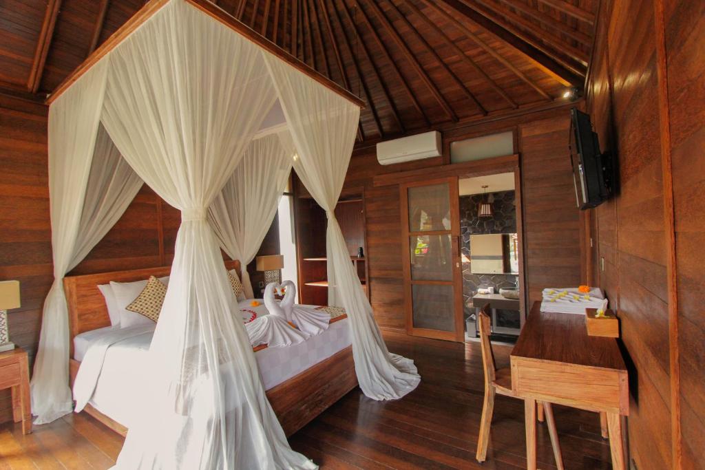 a bedroom with a bed with curtains and a desk at Villa D'Uma in Ubud