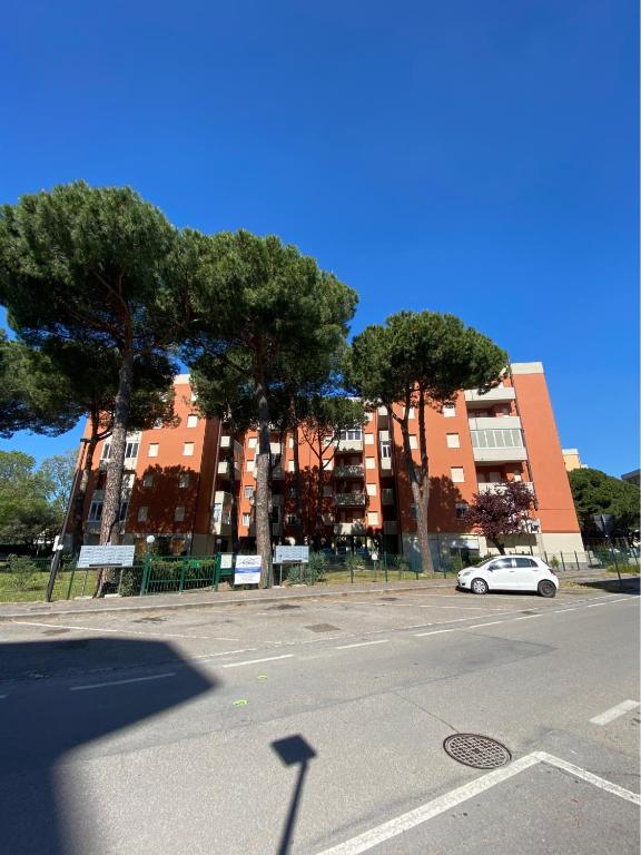 a white car parked in front of a building with trees at VARIE STRUTTURE Queste strutture NON FORNISCE lenzuola da letto e asciugamani in Lido Adriano