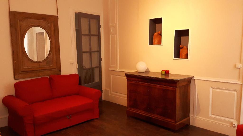 a living room with a red chair and a mirror at Les Boiseries in Dole