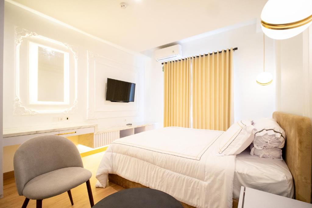 ein Schlafzimmer mit einem Bett und einem Stuhl und einem Fernseher in der Unterkunft Mataram City 327 by We Stay in Kejayan