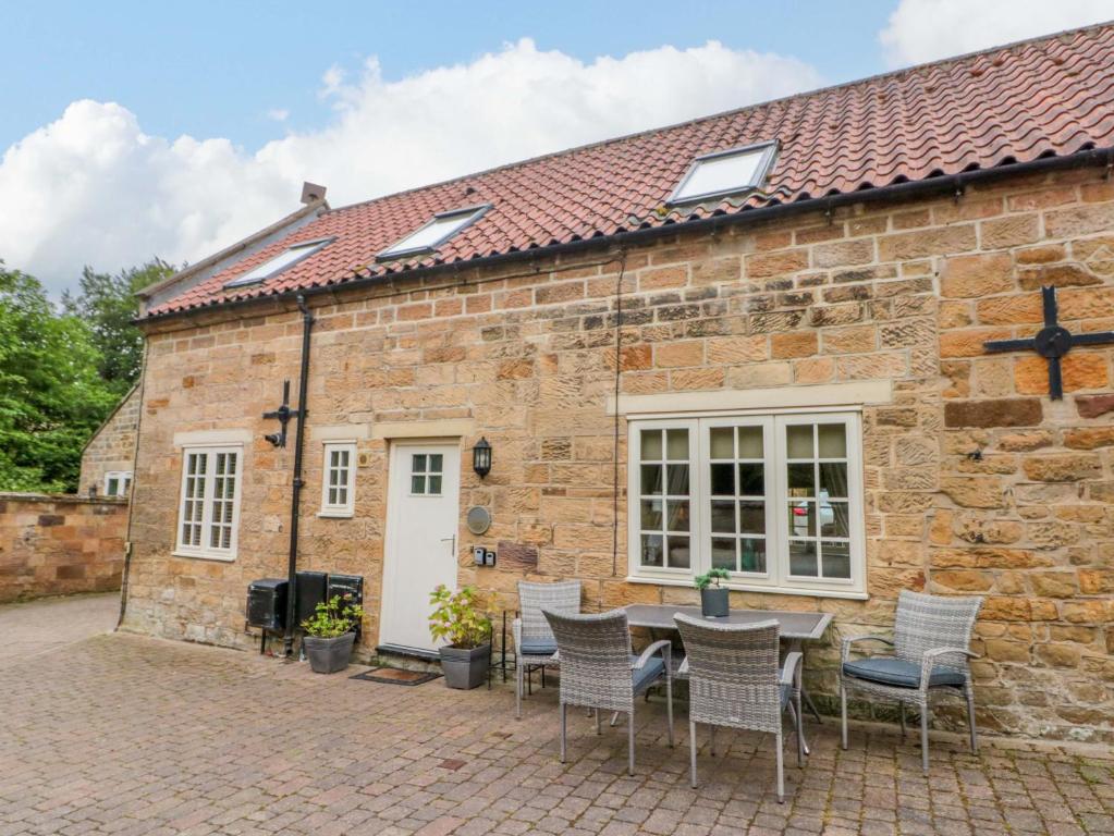 a stone cottage with a table and chairs in front of it at Clematis Cottage in Whitby
