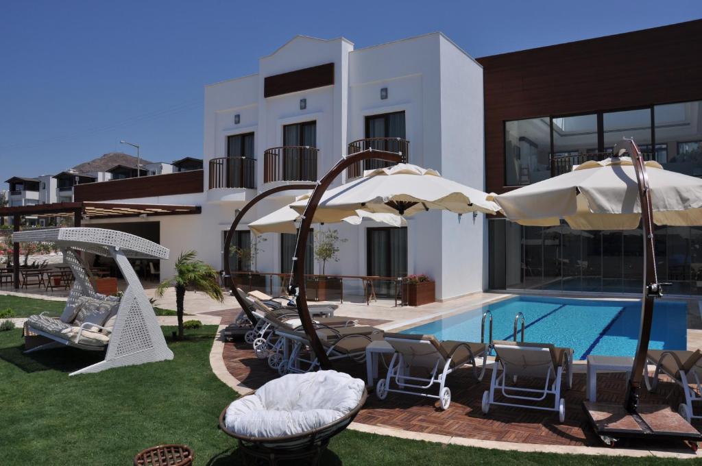 a pool with chairs and umbrellas next to a building at Small Beach Hotel in Turgutreis