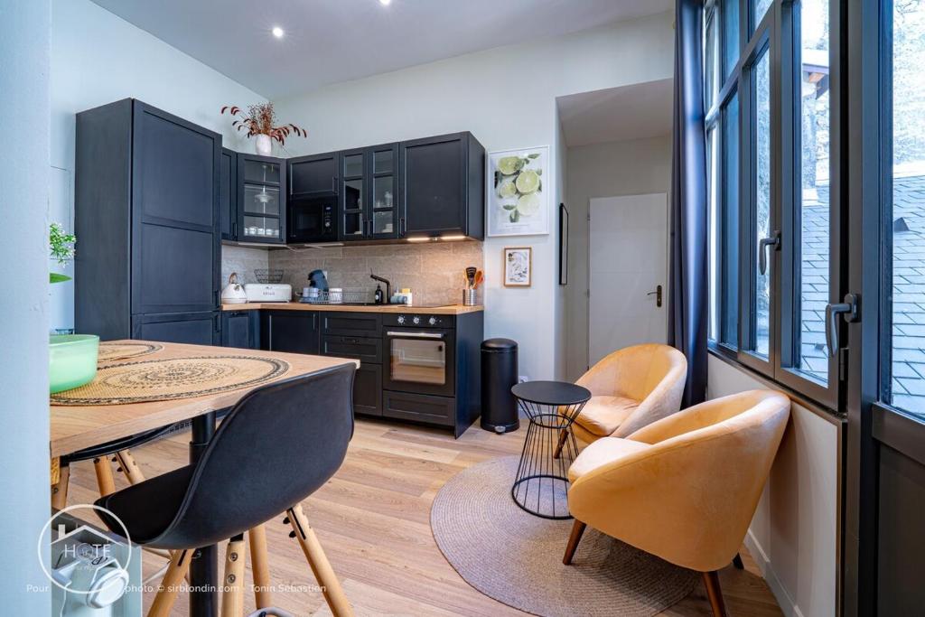 Una cocina con gabinetes negros y una mesa y sillas. en Chic l Ascenseur l Terrasse centre ville, en Chambéry