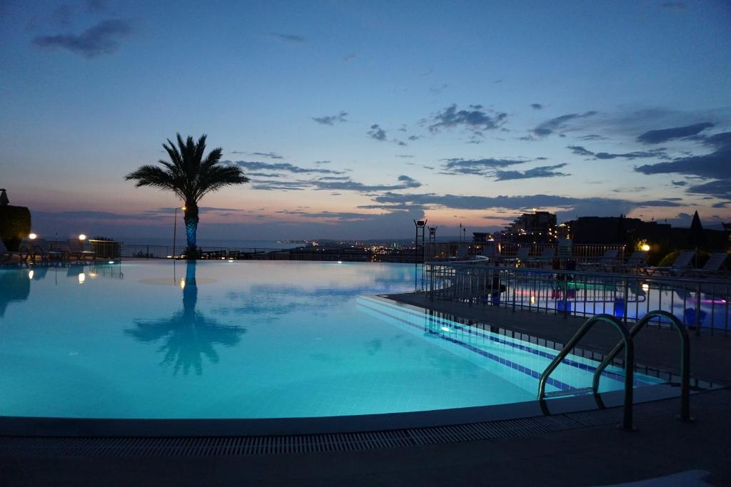 a large swimming pool with a palm tree in the background at Sunset Beach Vip 1 Residences in Konaklı