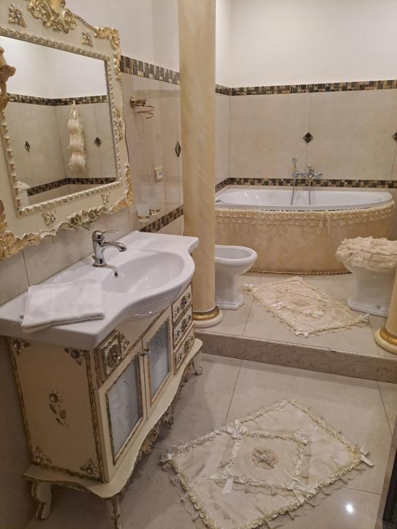 Un baño con lavabo, bañera y espejo. en Luxury House, en Catania
