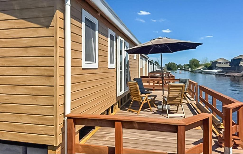 a wooden deck with chairs and an umbrella at Nice Home In Breukelen in Breukelen