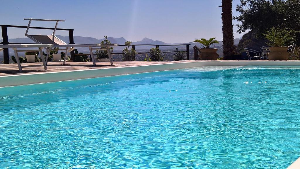 a blue swimming pool with a chair and a table at Estuario rooms in Castellammare del Golfo