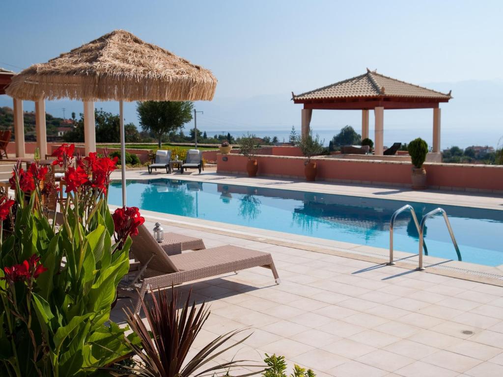 a swimming pool with chairs and a straw umbrella at Villa Inn Messinia in Kalamaki Messinia