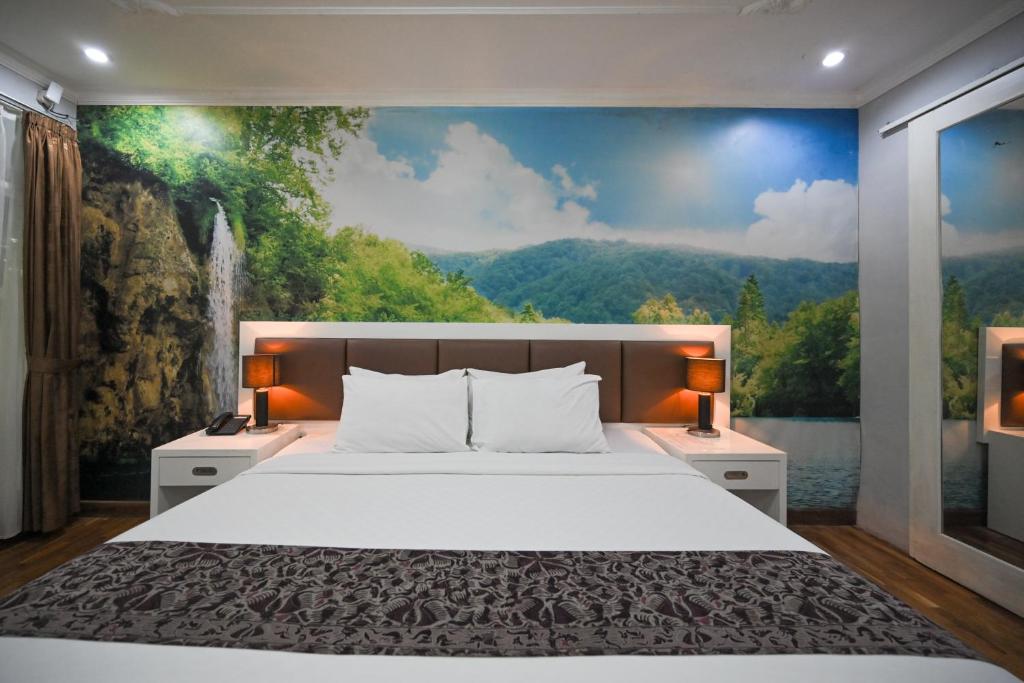 a bedroom with a large bed with a painting on the wall at The Taman Ayu in Seminyak