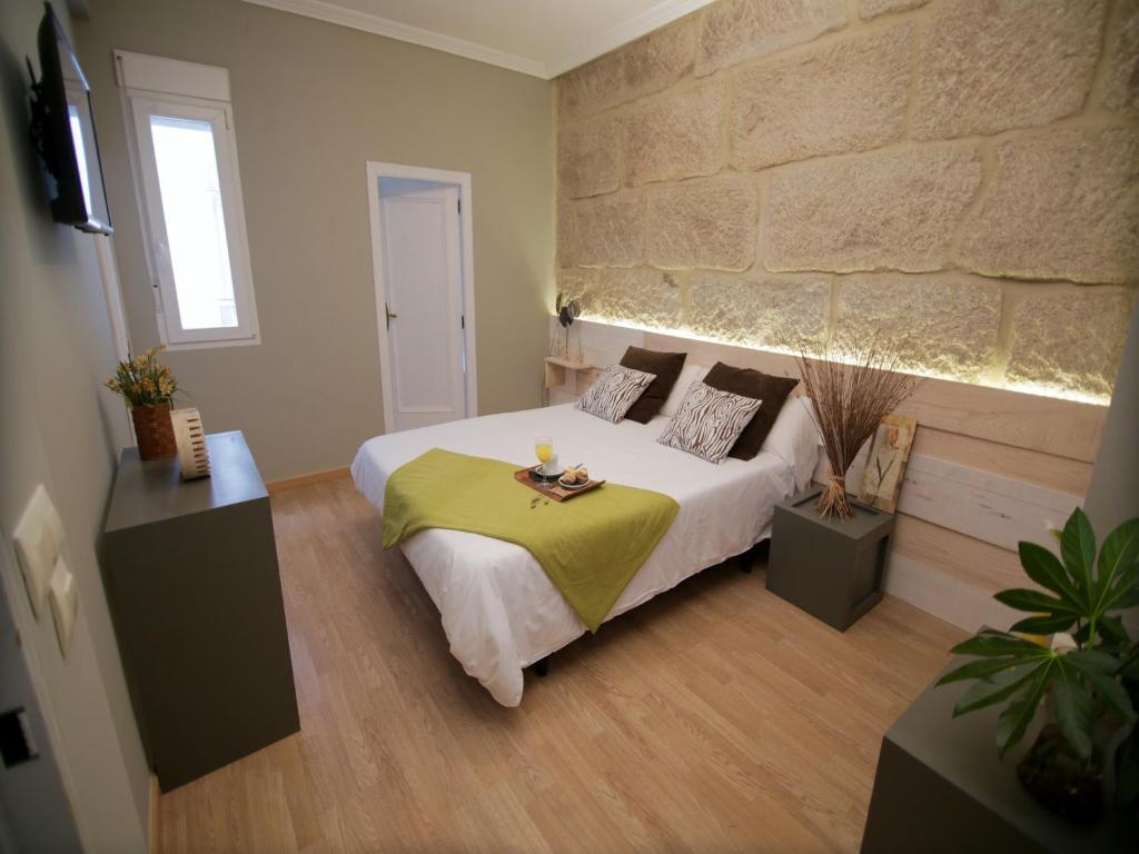 a bedroom with a bed and a stone wall at Hotel Alda Estación Vigo in Vigo