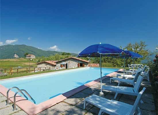 een zwembad met stoelen en een blauwe parasol bij Agriturismo Summer in Gallicano