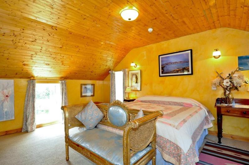 a bedroom with a bed and a chair in a room at Errisbeg House B&B in Roundstone