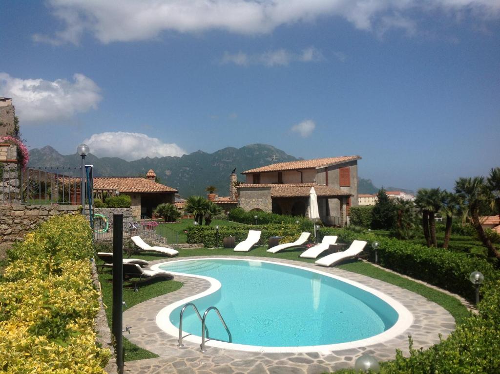 einen Pool in einem Garten mit Stühlen und einem Gebäude in der Unterkunft Villa Minuta in Scala