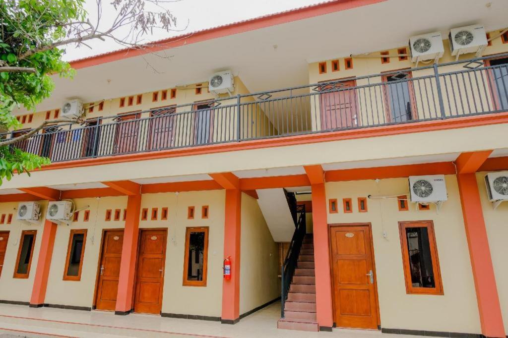 ein Gebäude mit orangefarbenen Türen und einem Balkon in der Unterkunft Hotel O Panderman Residence in Karangtengah
