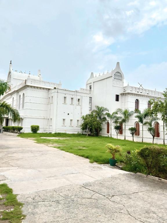 a white building with palm trees in front of it at BUDDHA HERITAGE RESORT in Bodh Gaya