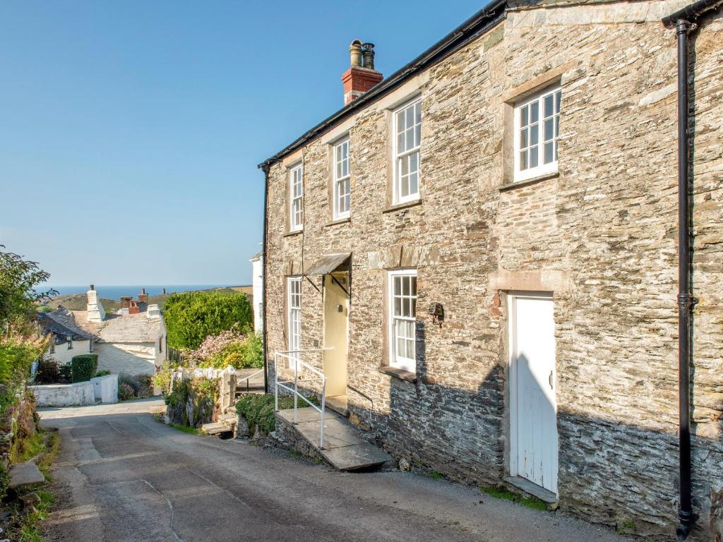 an old stone house with a white door on a street at Trevivian House in Boscastle