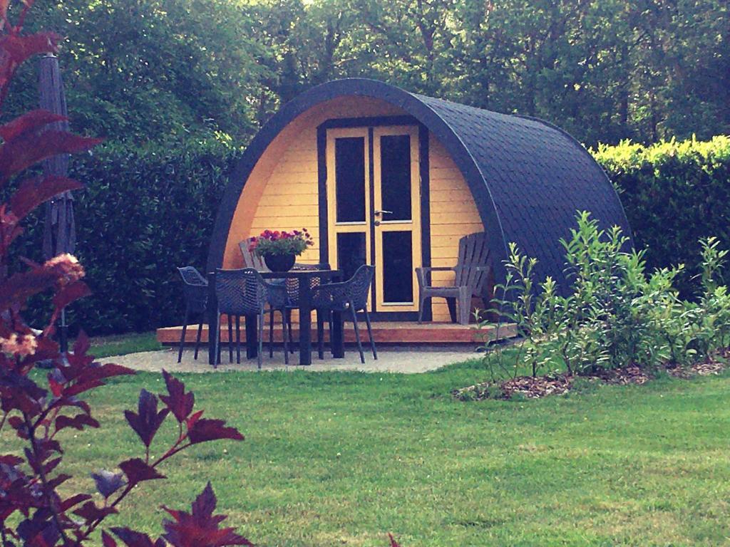 a dome tent with a table and chairs in a yard at Luxe woodlodge in bosrijke omgeving incl eigen douche en keuken in Bornerbroek