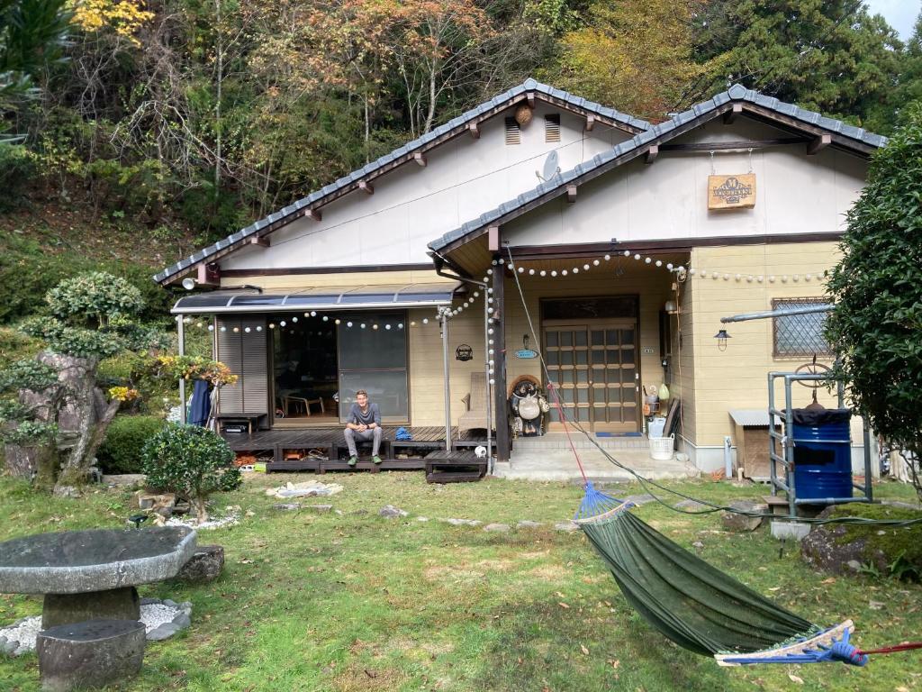 a man sitting in front of a house at Monet House モネハウス in Shimo-horado