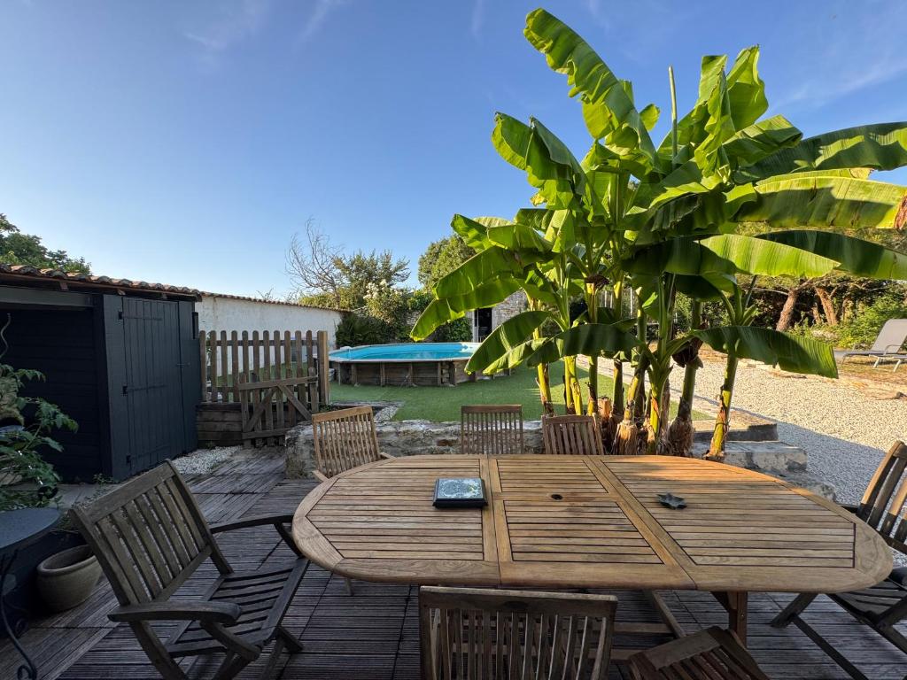 un tavolo e sedie di legno su un patio di Marais Inn, maison typique avec piscine et jardin arboré, 10 kms Niort a Sansais