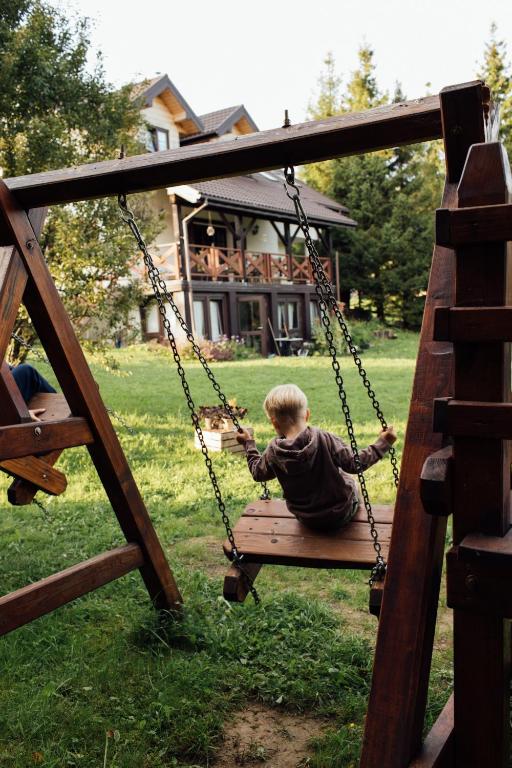 a boy sitting on a swing in a yard at Wetlinowo in Wetlina