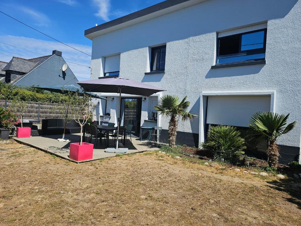 une maison avec un patio avec un parasol et des palmiers dans l'établissement La Govelle, au Pouliguen