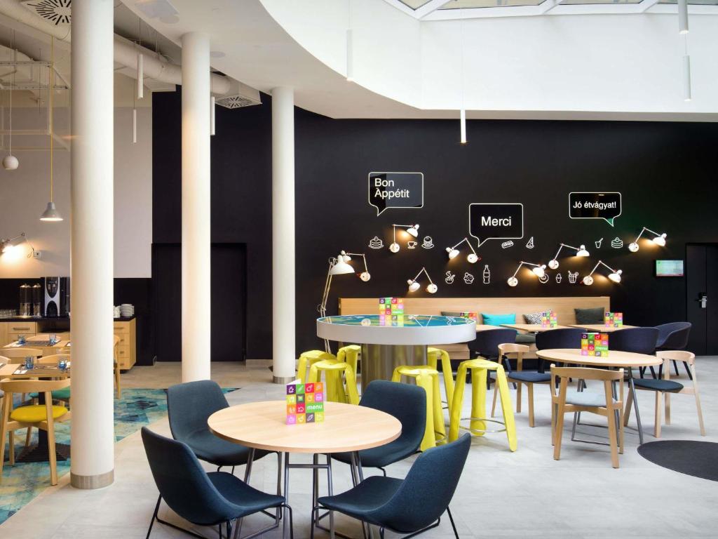 a restaurant with tables and chairs and signs on the wall at Ibis Styles Budapest Center in Budapest