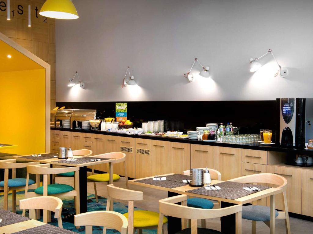 a restaurant with tables and chairs and a counter at Ibis Styles Budapest Center in Budapest