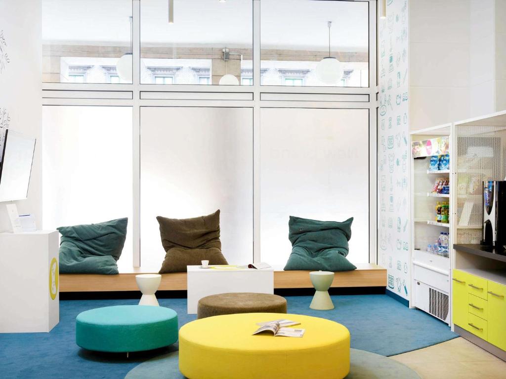 a living room with a yellow ottoman and a table at Ibis Styles Budapest Center in Budapest