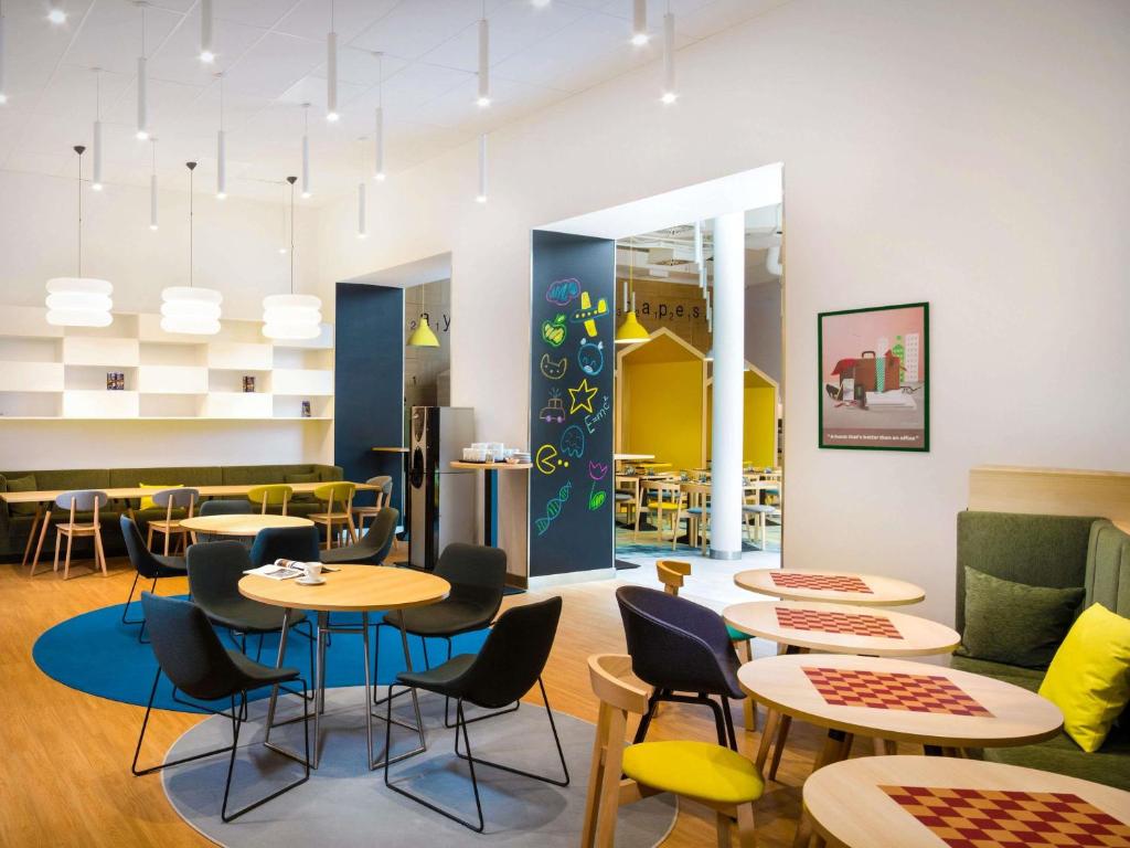 a restaurant with tables and chairs in a cafeteria at Ibis Styles Budapest Center in Budapest