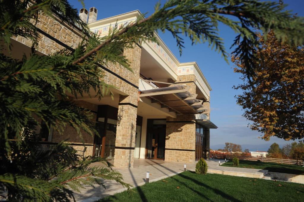 un grand bâtiment en briques avec une pelouse devant lui dans l'établissement Agapi Luxury Hotel, à Kato Loutraki
