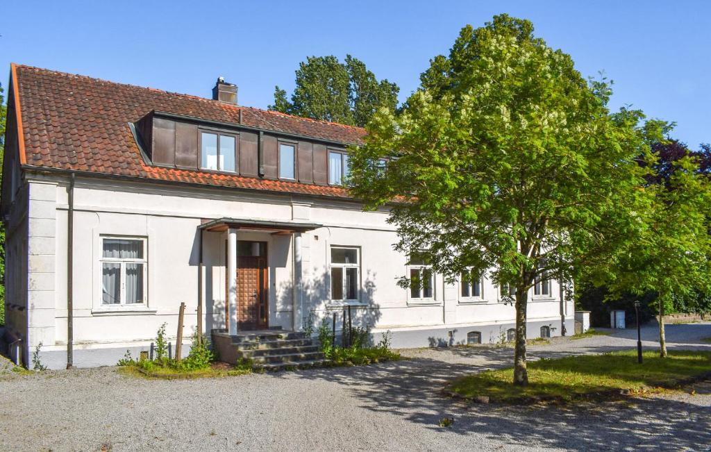 a white house with a tree in front of it at Beautiful Home In Flyinge in Flyinge
