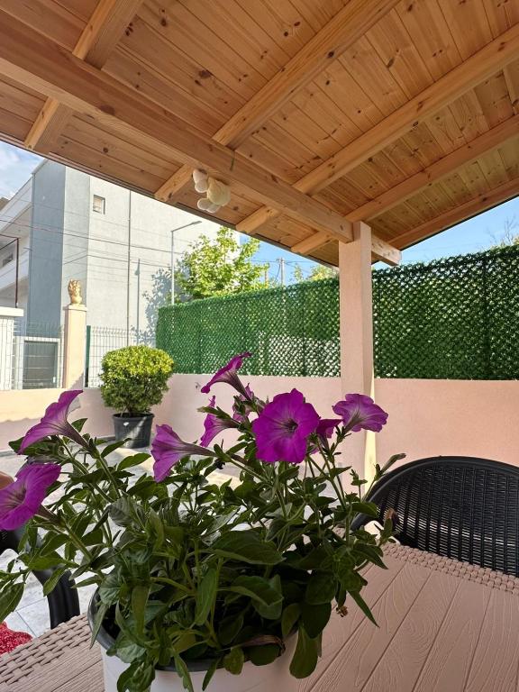 a vase of purple flowers sitting on a table under a wooden roof at Dori Apartment in Vlorë