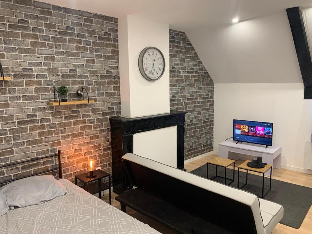 a bedroom with a bed and a clock on a brick wall at Cosy Loft New-Yorkais in Guingamp