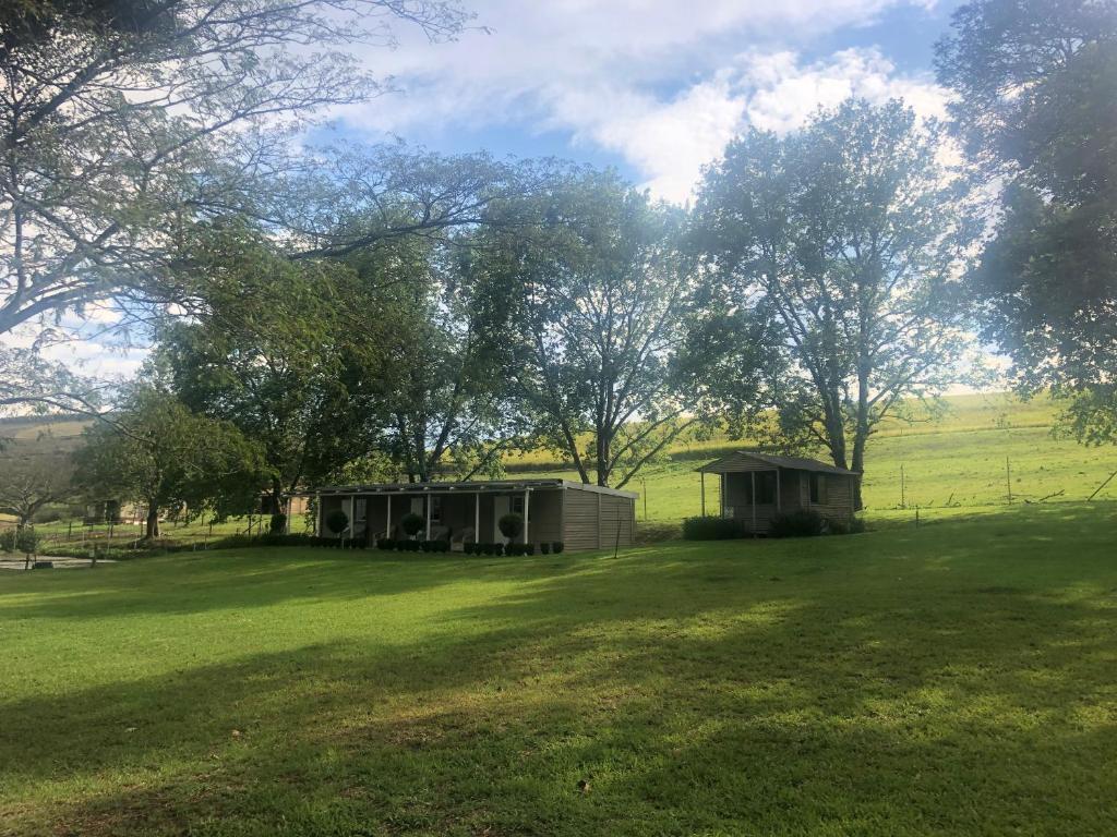 a small cabin in a field with trees and grass at The Pastures Eston Farm Stay in Mid Illovo