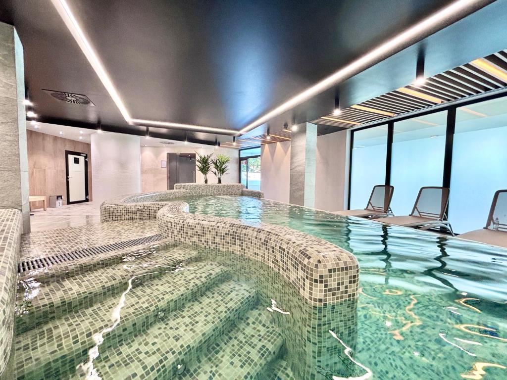 a large swimming pool with couches and chairs at Baltic Waves Resort & SPA Międzyzdroje 3 in Międzyzdroje