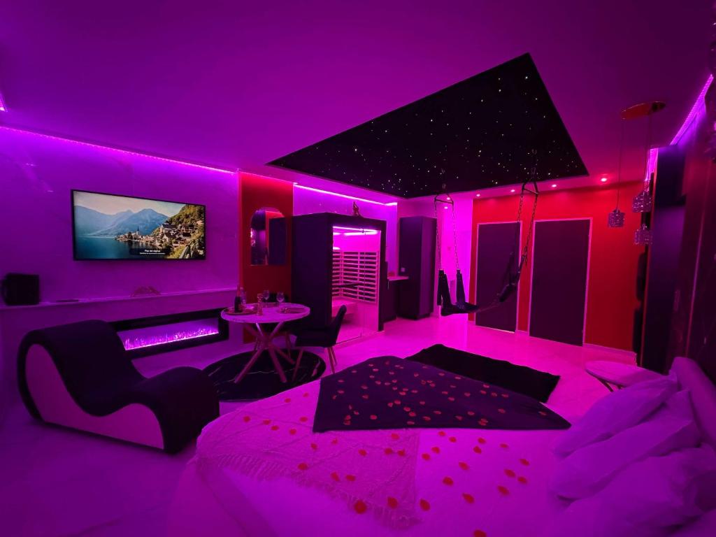 Cette chambre violette comprend un lit et une table. dans l'établissement Suite Secrète Love Room, à Callas