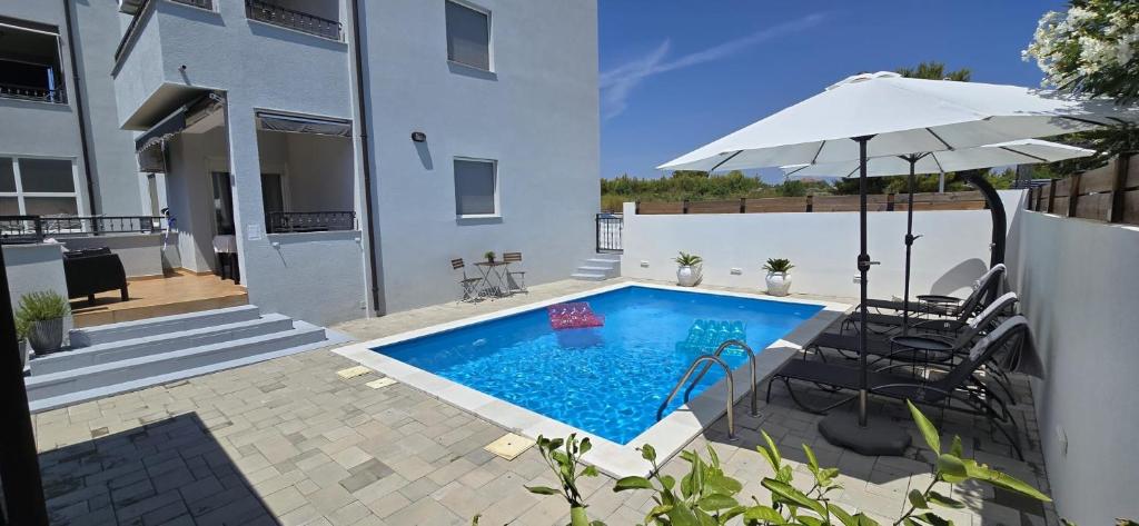a swimming pool with an umbrella next to a house at Apartment Alicia with private pool in Vodice