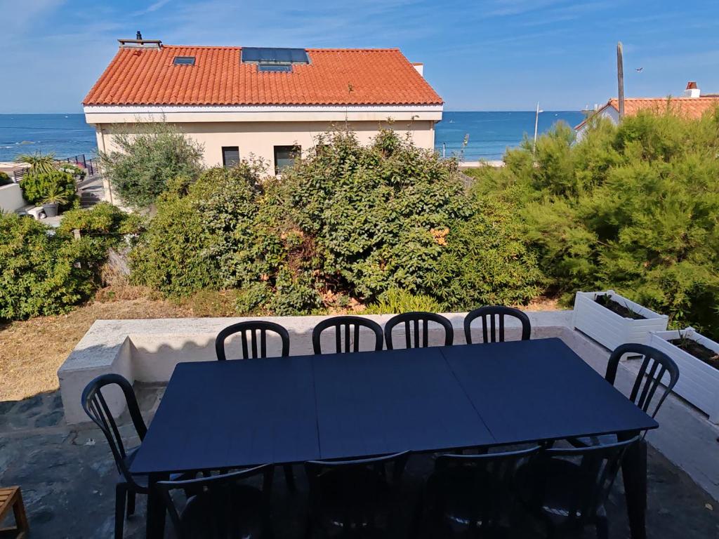 d'une table bleue et de chaises sur un balcon donnant sur l'océan. dans l'établissement Tanchet Beach House, à Les Sables-dʼOlonne