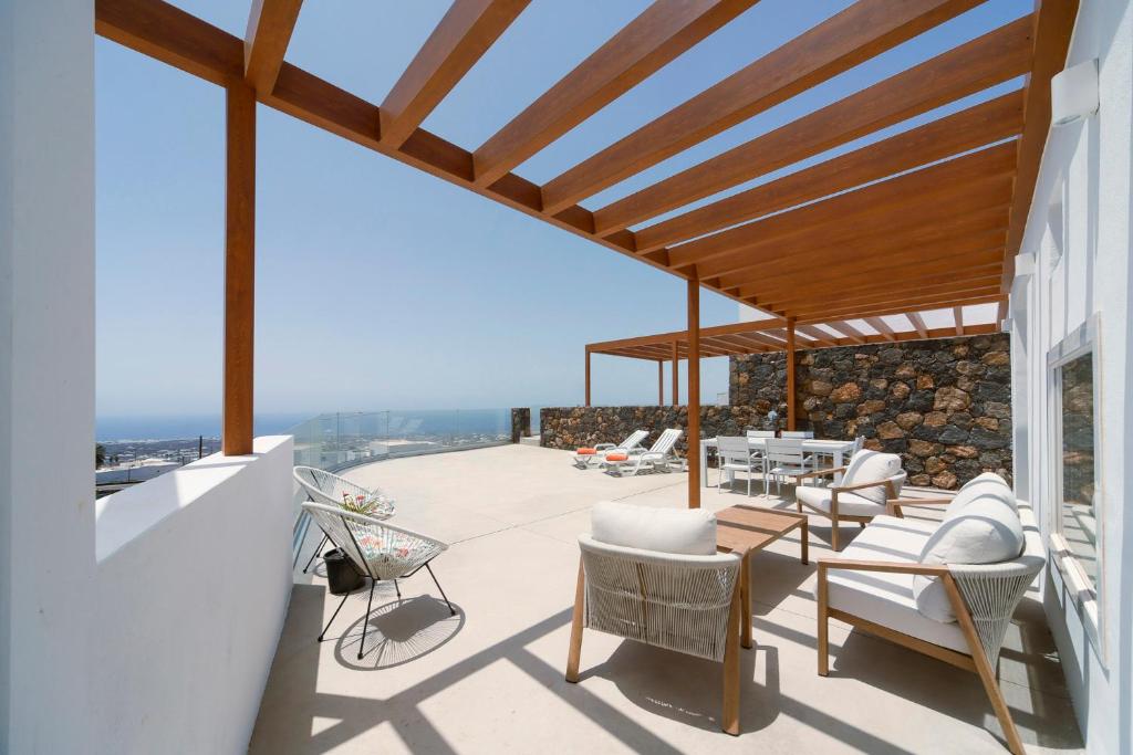 a patio with white chairs and a wooden roof at Luxury House La Maison II in Tías