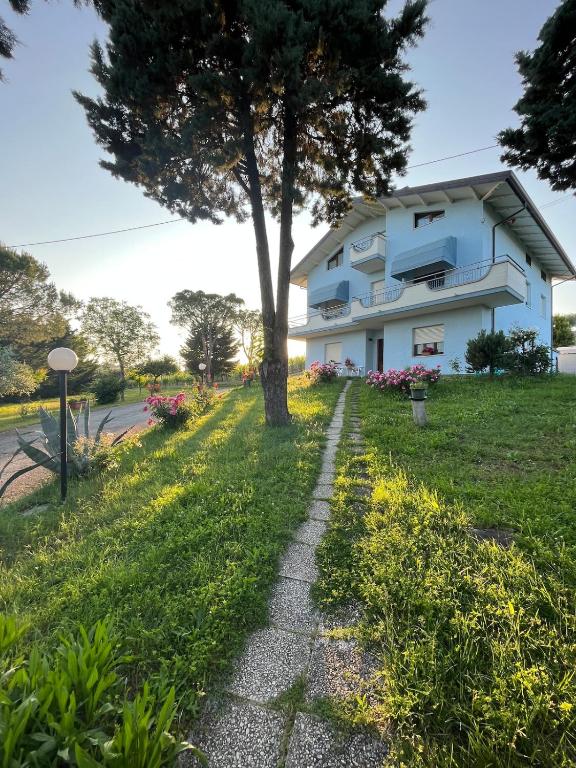 a tree in front of a white house at Appartamento Mansarda nel verde in Tavullia