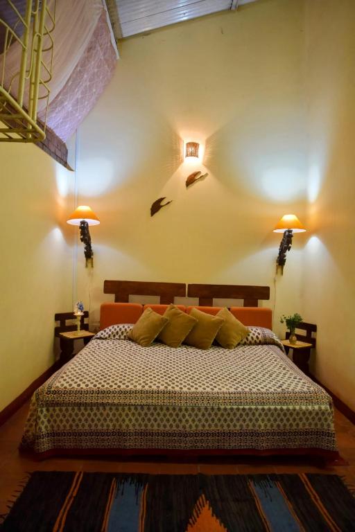 a bedroom with a bed with two lamps on the wall at Shantidarshan Homestay in  Amboli 