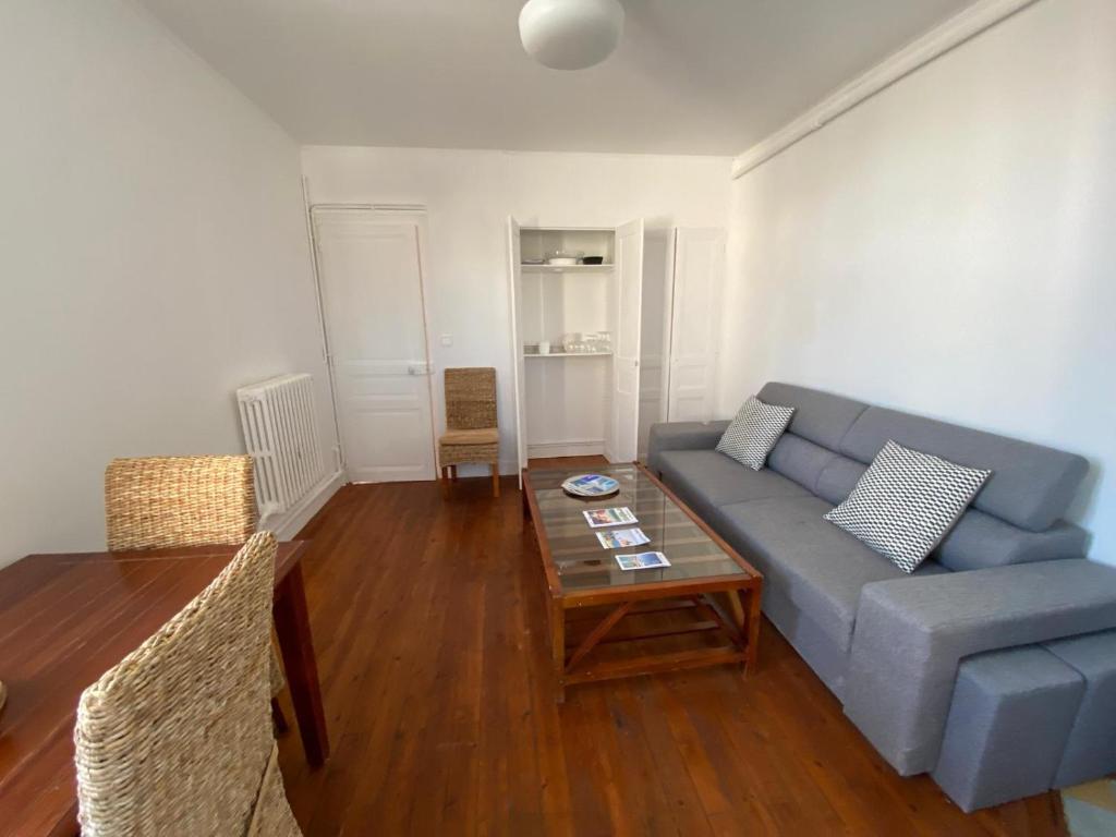 un salon avec un canapé bleu et une table dans l'établissement Cocon Appartement Hyper-centre proche plage et marché - 2 chambres, au Pouliguen