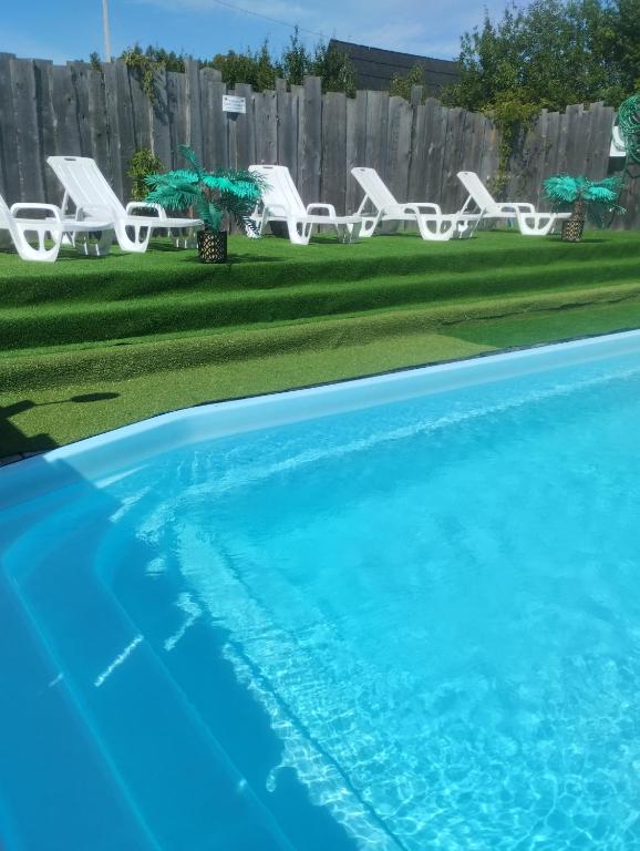 a swimming pool with white chairs and chairs in a yard at Willa Rycerz in Niedzica Zamek
