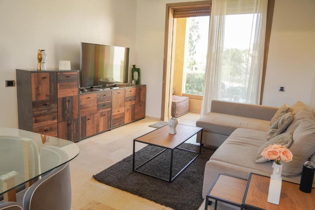 a living room with a couch and a tv at Appartement moderne à Marrakech Piscine, Jardin & fibre in Marrakech