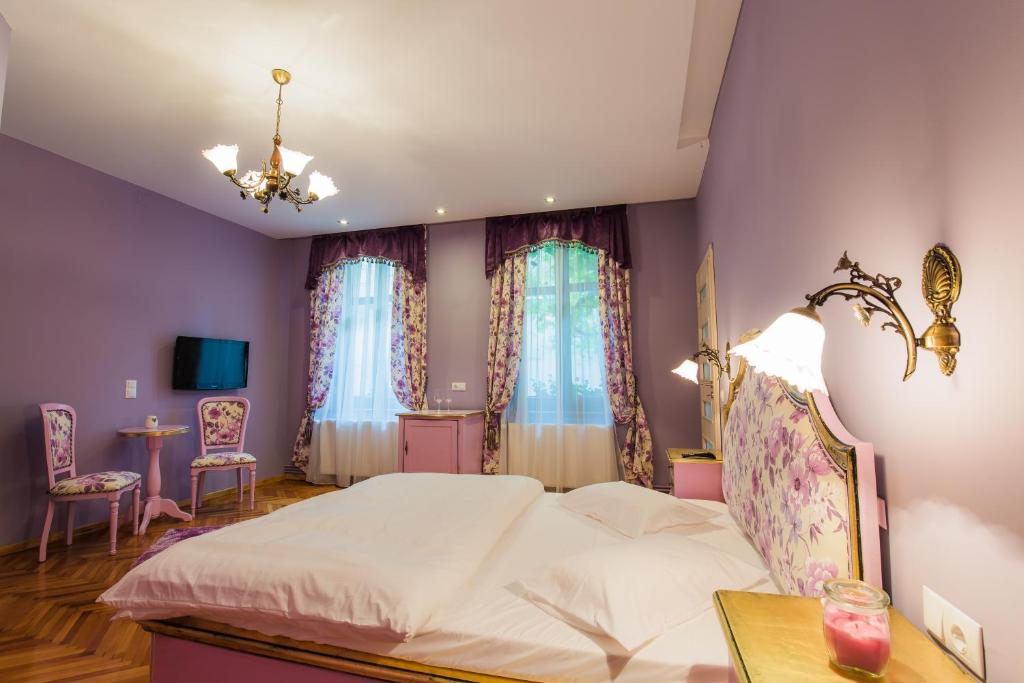 a bedroom with a white bed and two windows at Pensiunea Casa Helis in Sibiu