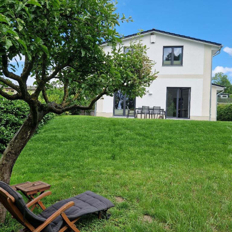a chair and a table in the grass next to a house at Ferienhaus Marie in Wittenbeck
